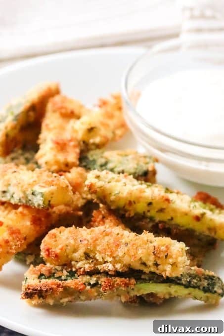 Close-up of crispy Parmesan Zucchini Fries with green herbs and cheese visible