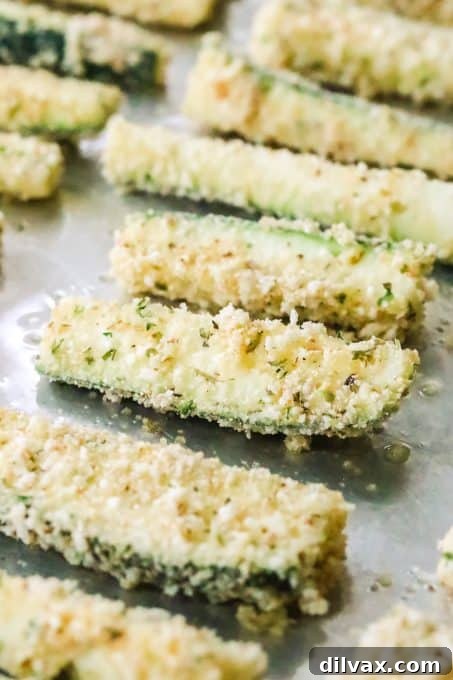 Zucchini spears coated in a seasoned Parmesan breading on a tray