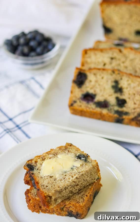Buttered slices of blueberry banana bread arranged beautifully on a plate, highlighting the tender crumb and juicy berries, ready to be enjoyed.