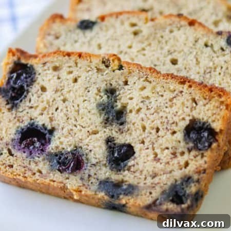 Thick layers of moist banana bread speckled with blueberries, ready to be served.