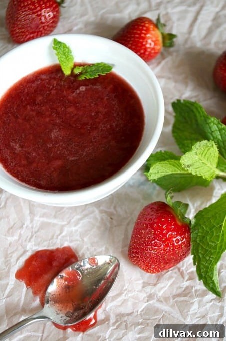 The perfect 3 Ingredient Strawberry Sauce for ice cream, pancakes, waffles, and more! In a small bowl, garnished with fresh mint.