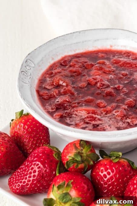 A bowl of fresh 3-Ingredient Strawberry Sauce with a spoon.