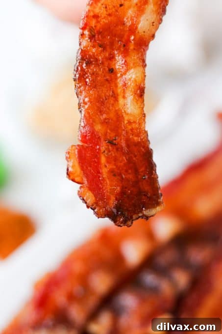 A single slice of Cajun candied bacon showing its crispy, seasoned texture, ready for a close-up.