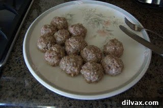 A vibrant, close-up shot of a plate of spaghetti and homemade baked meatballs, garnished with fresh herbs and Parmesan cheese.