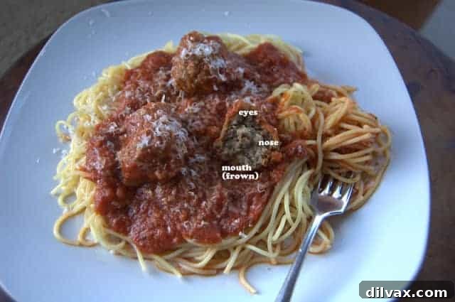 Close-up of a partially eaten meatball, showing a humorous face-like indentation.