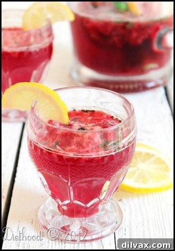 Raspberry Lime Soda Lemonade, a pink fizzy drink with raspberries and lime wedges.