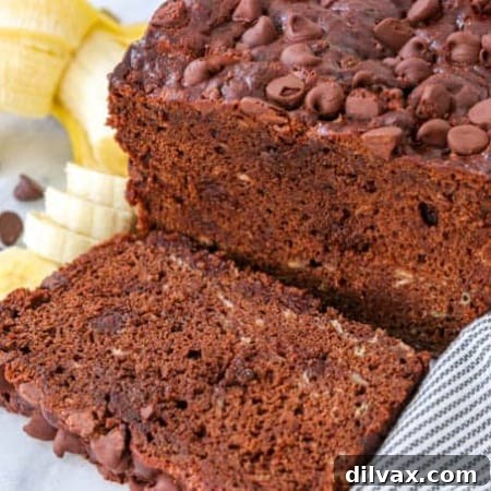 A loaf and slice of Double Chocolate Banana Bread on a marble cutting board.