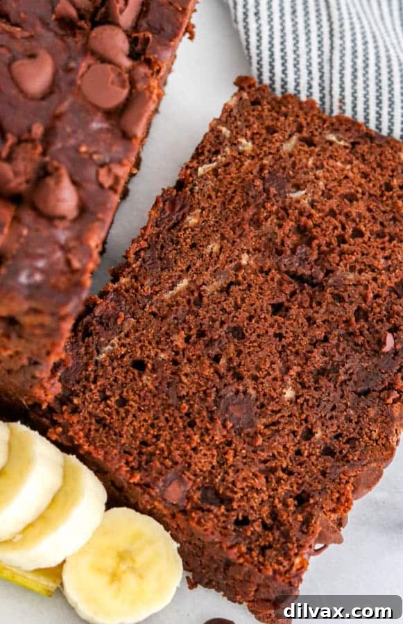 Decadent Double Chocolate Banana Loaf 7 A delectable slice of Double Chocolate Banana Bread, moist and rich with chocolate, presented alongside fresh banana slices.