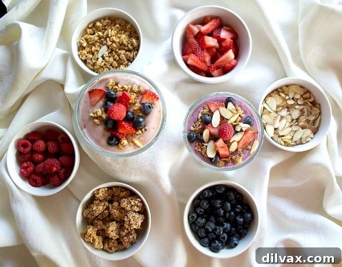 A colorful array of ingredients for a breakfast parfait bar including berries, nuts, granola, and Silk Dairy-Free Yogurt alternatives, arranged invitingly.