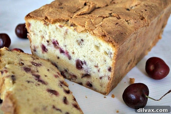 A close-up view of the Cherry Pound Cake, showing the browned crust and juicy cherries peeking through the rich crumb.