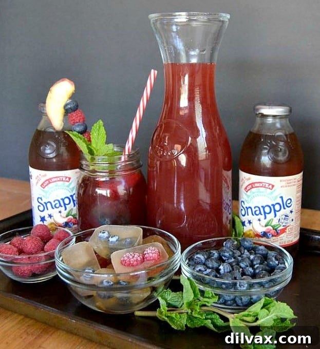 Variety of Snapple bottles, including Lady LiberTEA, displayed with fresh fruit, emphasizing choices for summer.