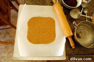 Graham cracker dough rolled out between two pieces of parchment paper