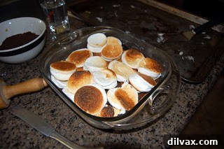 Assembled S'mores Bars with chocolate and marshmallows layered on the crust