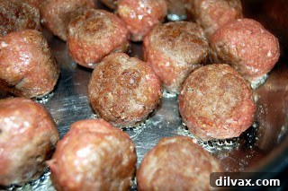Meatballs browning in a hot skillet.
