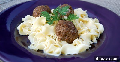 Cooked meatballs simmering in a creamy sauce in a casserole dish.