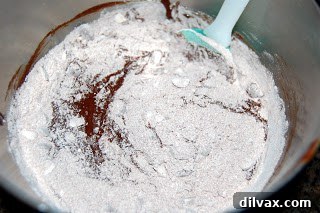 Folding flour mixture into the brownie batter with a spatula.