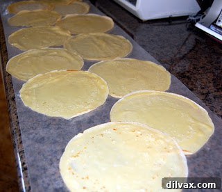 Stack of cooked crepes separated by waxed paper.