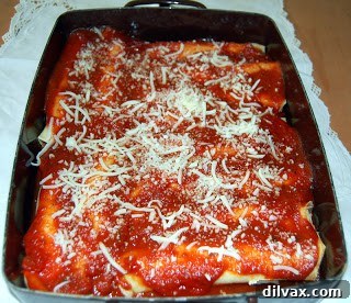Manicotti in baking dish, covered with sauce and cheese, ready for baking.