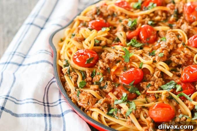 An easy weeknight meal with linguine, tomatoes, sausage, and a savory sauce, all cooked in a single pot for minimal cleanup.