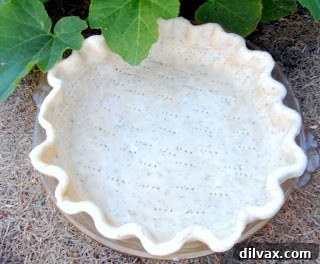 A blind-baked quiche crust in a pie pan, ready for the savory filling.