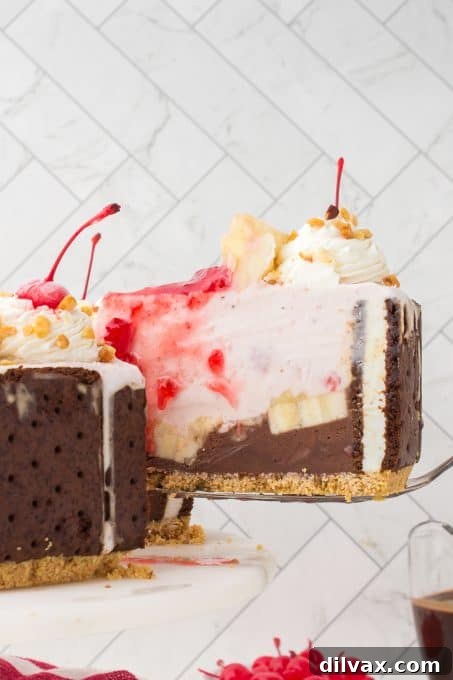 A beautiful Banana Split Ice Cream Cake, showing layers of ice cream sandwiches, chocolate and strawberry ice cream, pineapple, whipped cream, nuts, and cherries.