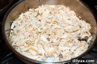 Shredded chicken cooking in a pan