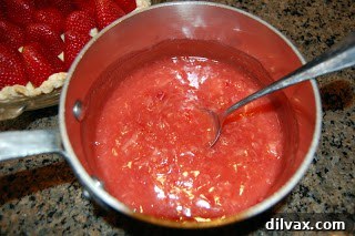 Strawberry glaze mixture thickening in a saucepan