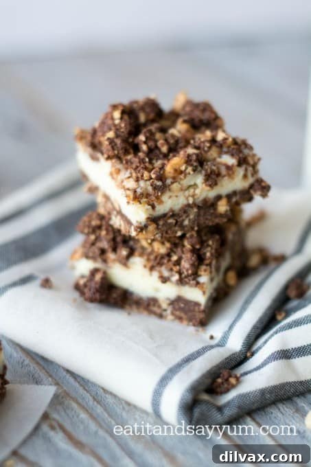A close-up view of a Chocolate Crumble Cheesecake Bar, showcasing the distinct layers of creamy cheesecake and the textured chocolate peanut crust.
