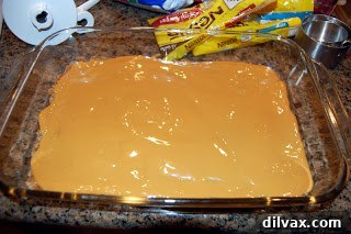 Spreading a layer of sweetened condensed milk over the bar dough.