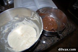 Marble cake batter carefully spooned into a round baking pan, showing layering.