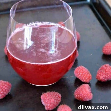 Homemade Raspberry Simple Syrup in a glass bottle with fresh raspberries