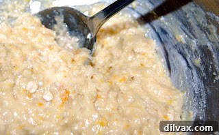 Muffin batter with orange zest being mixed in a bowl.
