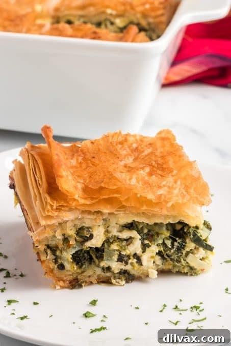 The delicious and vibrant green filling of spinach, eggs, and feta cheese, perfectly packed and layered between crisp sheets of golden phyllo dough for a homemade Spanakopita.