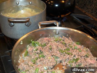 Browning ground beef with onions and green peppers in a skillet.