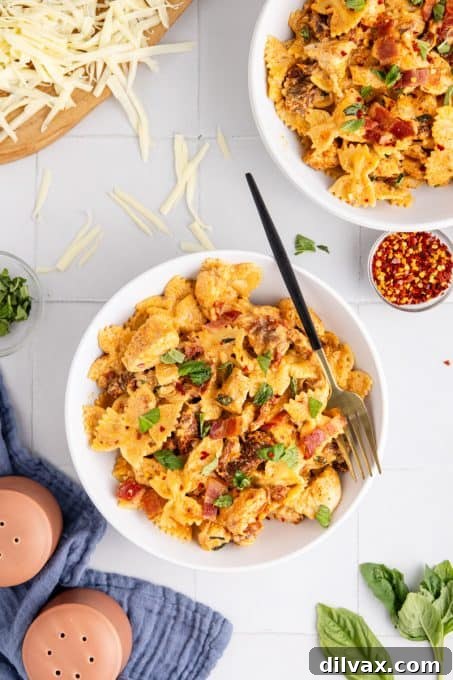 A serving of flavorful chicken and pasta dinner, featuring bow tie pasta, chicken, and sun-dried tomatoes in a rich, creamy sauce, garnished with fresh basil.