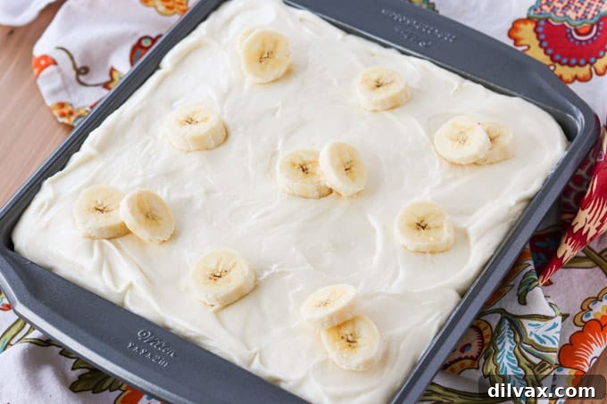 Golden Banana Cake with Velvety Cream Cheese Frosting 2 A beautifully frosted banana cake adorned with fresh banana slices on top.