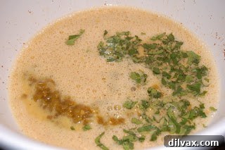Day 21 Chile Cheese Casserole Delight 3 A bowl showing a mixture of whisked eggs, diced green chiles, and cilantro, ready for the casserole.