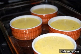 Crème Brûlée in a water bath, poised for gentle baking Ramekins filled with Crème Brûlée custard placed in a water bath, ready for oven