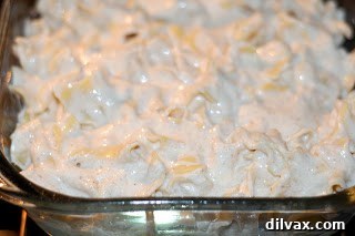 Image showing all the kugel ingredients, including noodles, breadcrumbs, and fruit, being mixed in a large bowl.