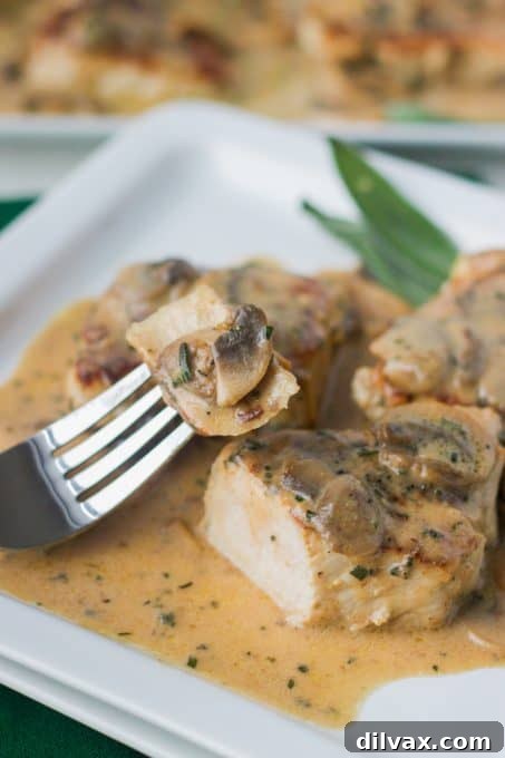 Tender Rosemary Pork Medallions Draped in Mushroom Wine Sauce 9 A fork taking a bite of a rosemary pork medallion with mushrooms and sauce.