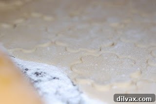 Sugar cookie dough being rolled out and cut into circles.
