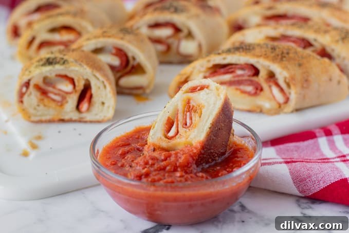 Dipping a golden-brown bread, generously stuffed with pepperoni and melted provolone cheese, into a bowl of vibrant marinara sauce.