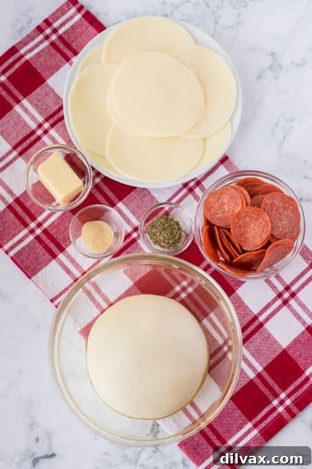 Essential ingredients for Pepperoni Bread laid out: pizza dough, sliced pepperoni, provolone cheese, and butter with seasonings.