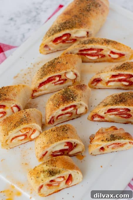 A cross-section of freshly baked pepperoni bread, showing the luscious layers of melted provolone cheese and spicy pepperoni encased in a golden pizza dough crust.