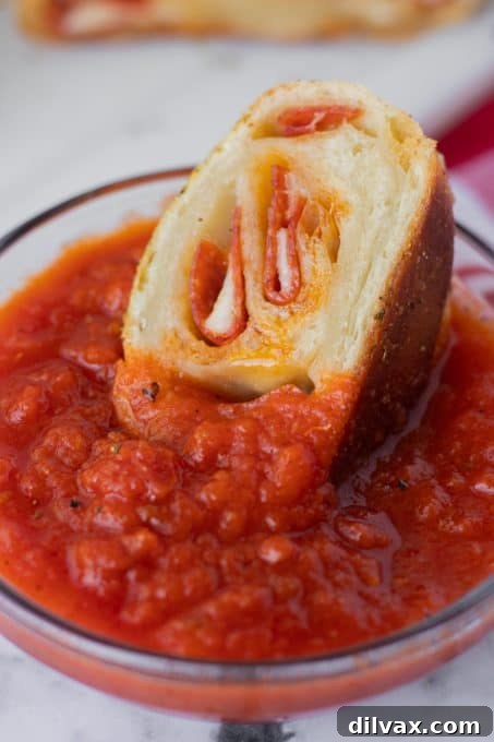 A perfectly baked slice of pepperoni bread, revealing the beautiful swirl of pepperoni and melted provolone cheese within.