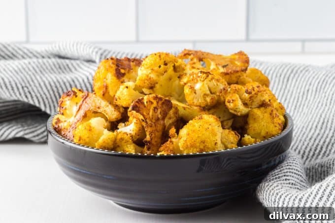 Cajun Curry Roasted Cauliflower 2 Golden-brown roasted cauliflower florets seasoned with curry and Cajun spices, served in a white bowl.