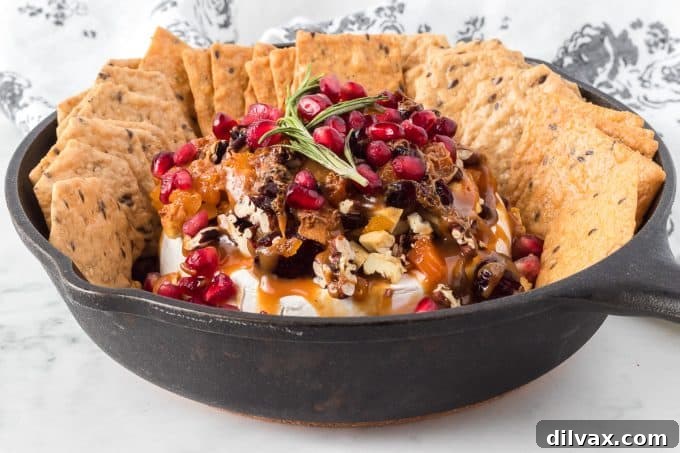 Melted Brie Bliss 2 A beautifully presented baked brie wheel, glistening with butterscotch sauce, surrounded by dried fruits and nuts, ready to be served.
