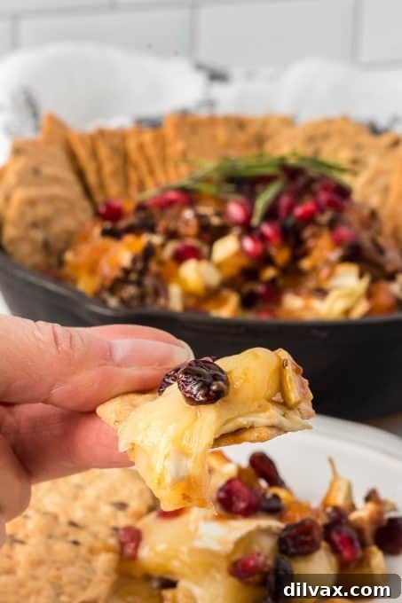 Melted Brie Bliss 11 A single bite of baked brie, perfectly melted and topped with fruit and nuts, lifted from the oven-safe dish.