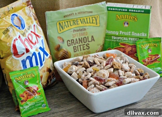 A selection of the key ingredients laid out: a bag of Chex Mix, Nature Valley Granola Bites, Annie's Fruit Snacks, and dried fruits, ready to be combined into a delicious snack.