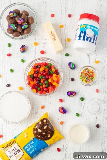 Colorful Easter Fudge 4 Essential ingredients for making white chocolate Easter Fudge laid out on a surface, including marshmallow crème, white chocolate chips, sugar, heavy cream, salt, butter, Cadbury Creme Eggs, Starburst Jelly Beans, and spring sprinkles.